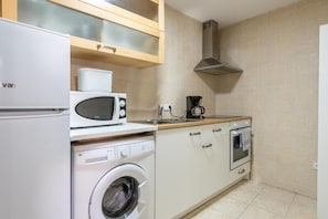 A compact kitchen with a washing machine, microwave, coffee maker, and oven. - Holiday Palma Apartments (Palma)