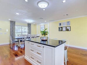A modern kitchen with white cabinetry, a black countertop, and a dining area with white chairs. - Charming Tampa retreat with a private hot tub (Tampa)