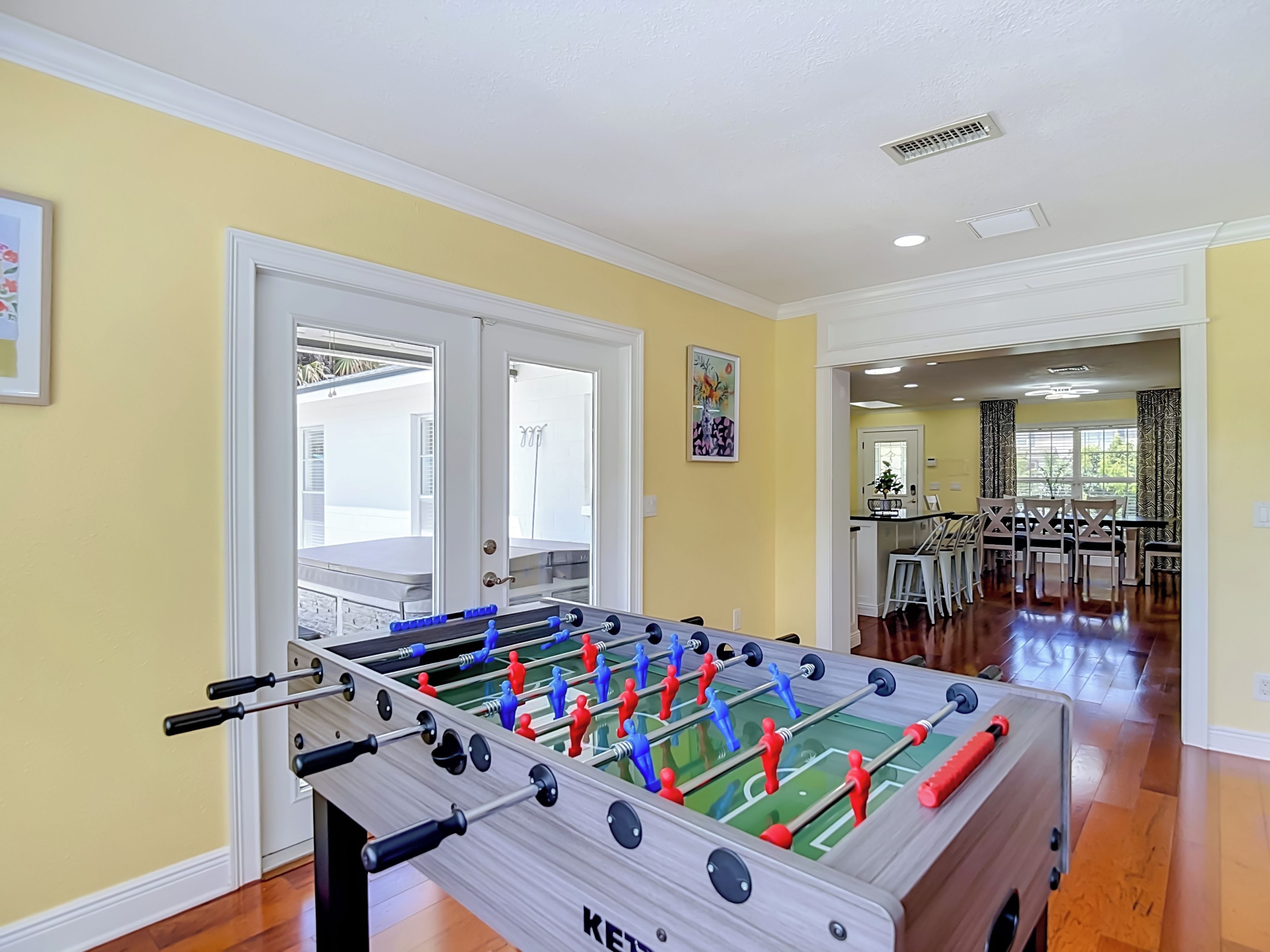 A foosball table in a room with yellow walls and wooden flooring.