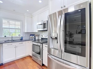 A modern kitchen with white cabinetry, stainless steel appliances, a microwave, and a built-in oven. - Charming Tampa retreat with a private hot tub (Tampa)