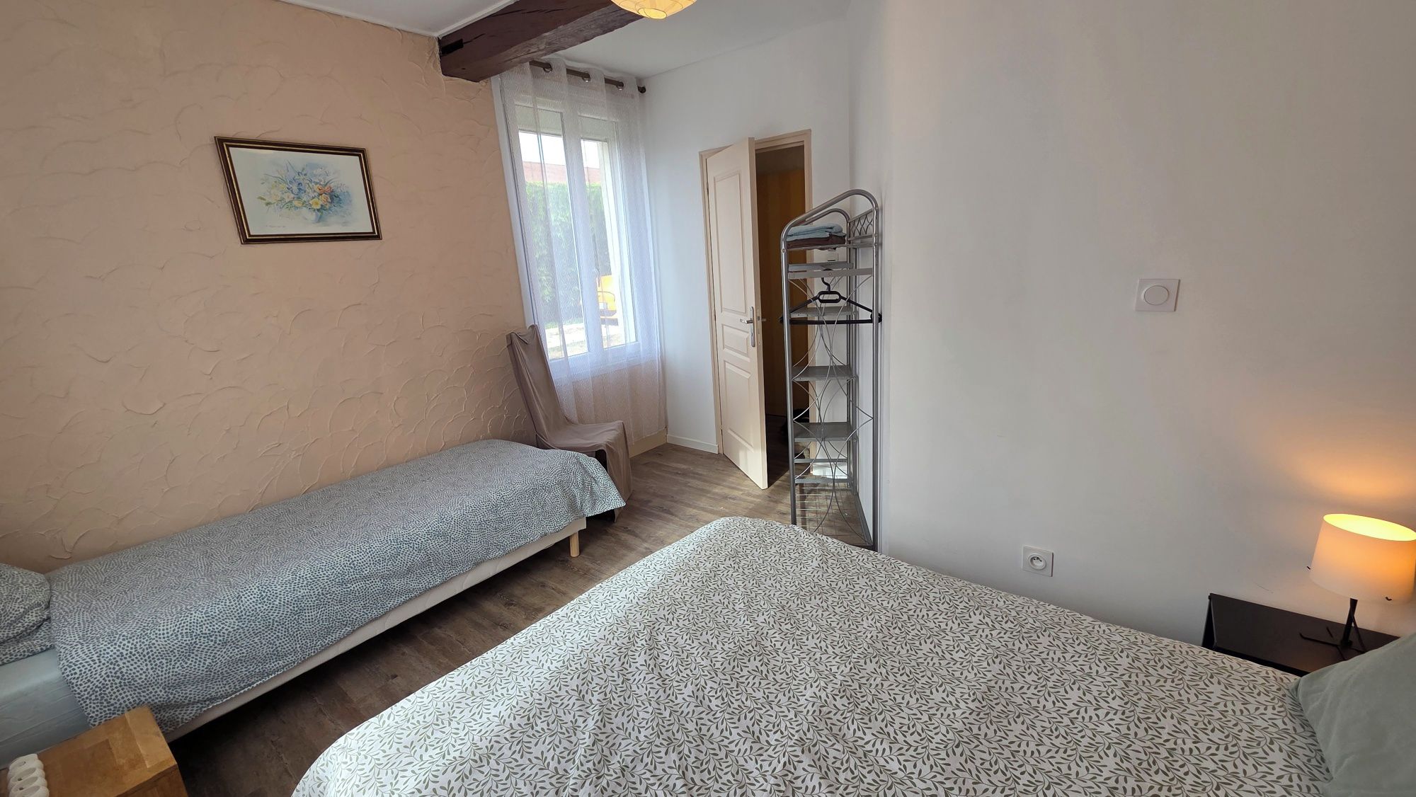 Un dormitorio con dos camas individuales, una silla, un armario y una ventana con cortinas.