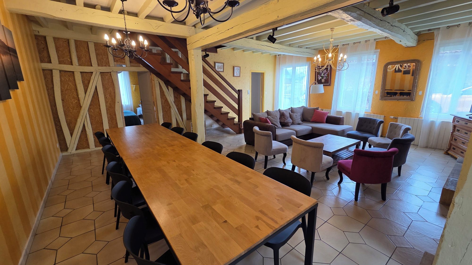 Una habitación amplia con una mesa de comedor de madera, varias sillas, un sofá y una escalera que lleva a otro nivel.