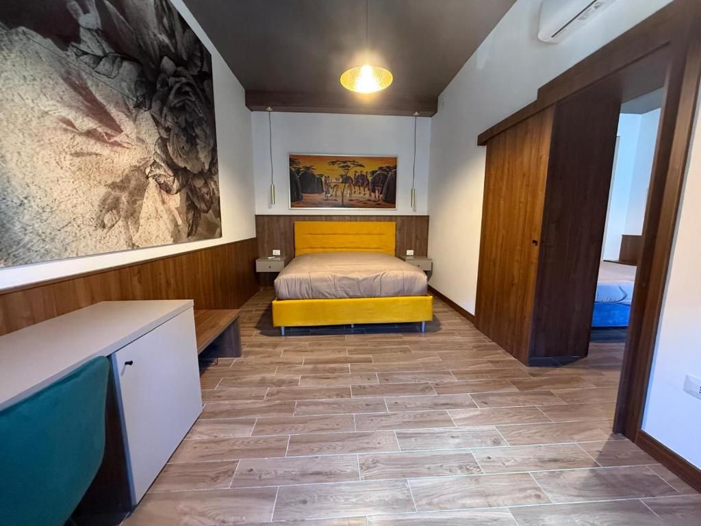 Une chambre à coucher avec un lit, un tableau accroché au mur, une petite armoire et une porte en bois.