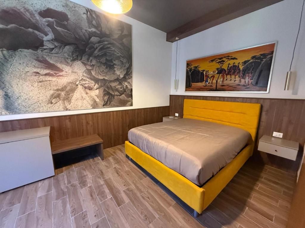 A bedroom with a bed, a nightstand, a bench, and a large painting on the wall.