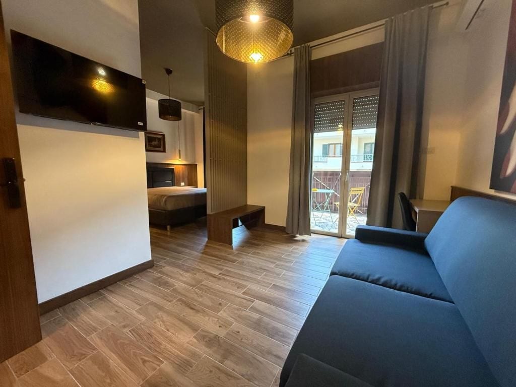 Een moderne woonkamer met een bank, een flatscreen televisie aan de muur en een trap naar een buitenruimte.