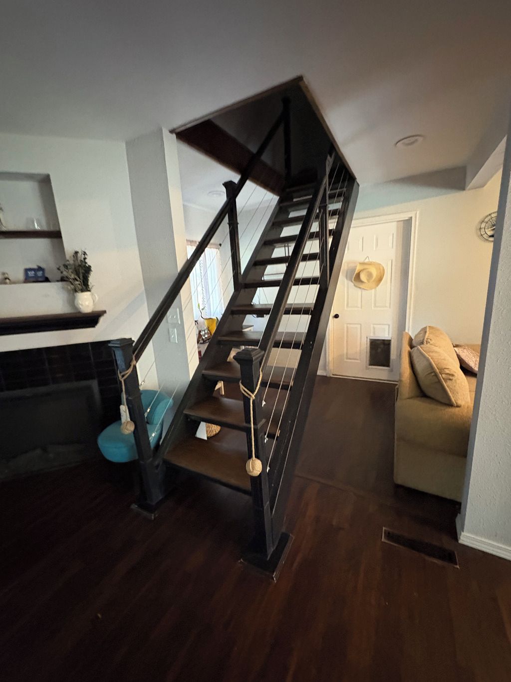 Una escalera de acabado oscuro que conduce a un rellano con una puerta y un reloj en la pared.