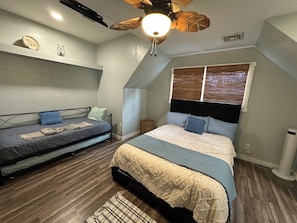 Une chambre à coucher avec un lit, un canapé, un ventilateur de plafond et une fenêtre.