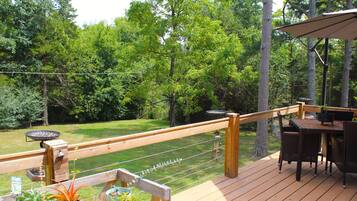 A wooden deck with outdoor furniture, a barbecue grill, and potted plants.