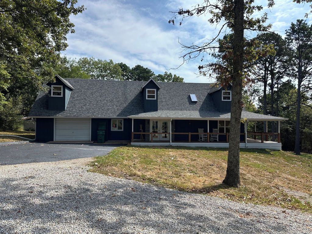 Une maison à deux étages avec un porche couvert, un garage et une allée.