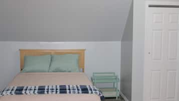 A bedroom with a bed, a nightstand, and a door.