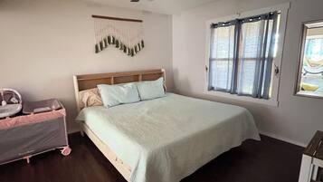 A bedroom with a bed, a ceiling fan, a window with curtains, and a wall-mounted decoration.
