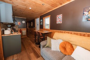 A cozy interior with a kitchenette, a dining area, and a seating area with a sofa and cushions.