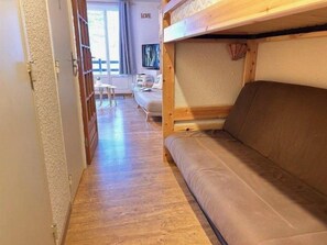A room with a bunk bed, a sofa, a small table, and a chair. - 50m from ski slopes, 1st floor, balcony, tv, ski locker, 24m², Risoul (Risoul)