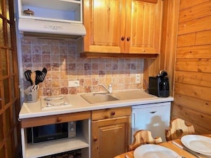 A compact kitchen with wooden cabinets, a microwave, a coffee maker, and a sink. - 50m from ski slopes, 1st floor, balcony, tv, ski locker, 24m², Risoul (Risoul)