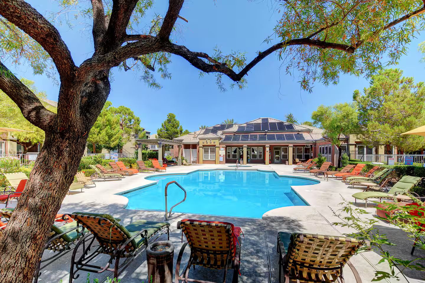 A pool area with lounge chairs and a building in the background.