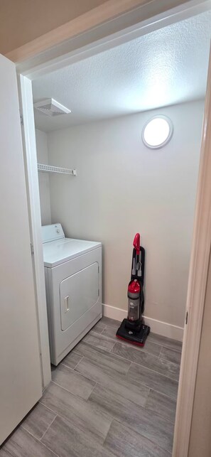A laundry room with a washing machine, a vacuum cleaner, and a ceiling vent. - Tuscano Condo Gem! SW Las Vegas Oasis (Las Vegas)