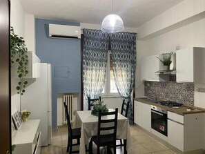 A compact kitchen with a dining table, chairs, a stove, and a radiator. - Apartment 'La Casa Di Kya - Universo Beach' with Sea View, Wi-Fi and Air Conditioning (Salerno)
