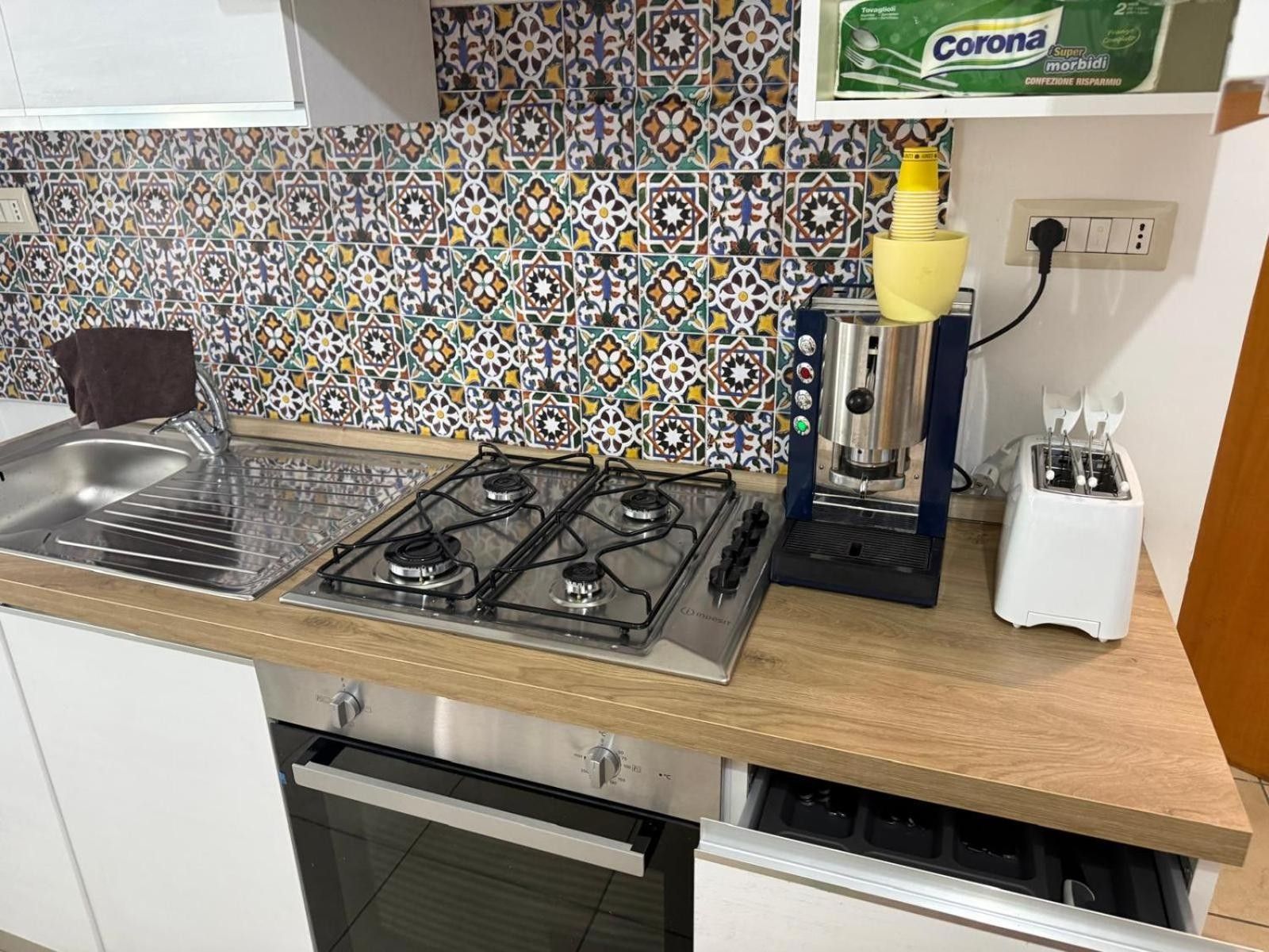 Una cocina con estufa a gas, un tostador y una botella de cerveza Corona.