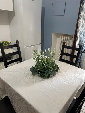 A dining table with a floral centerpiece, two black chairs, and a white tablecloth. - Apartment 'La Casa Di Kya - Universo Beach' with Sea View, Wi-Fi and Air Conditioning (Salerno)
