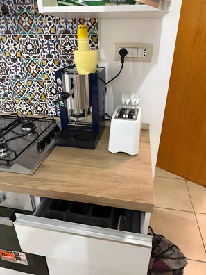 A kitchen with a gas stove, a coffee machine, a toaster, and a patterned backsplash. - Apartment 'La Casa Di Kya - Universo Beach' with Sea View, Wi-Fi and Air Conditioning (Salerno)