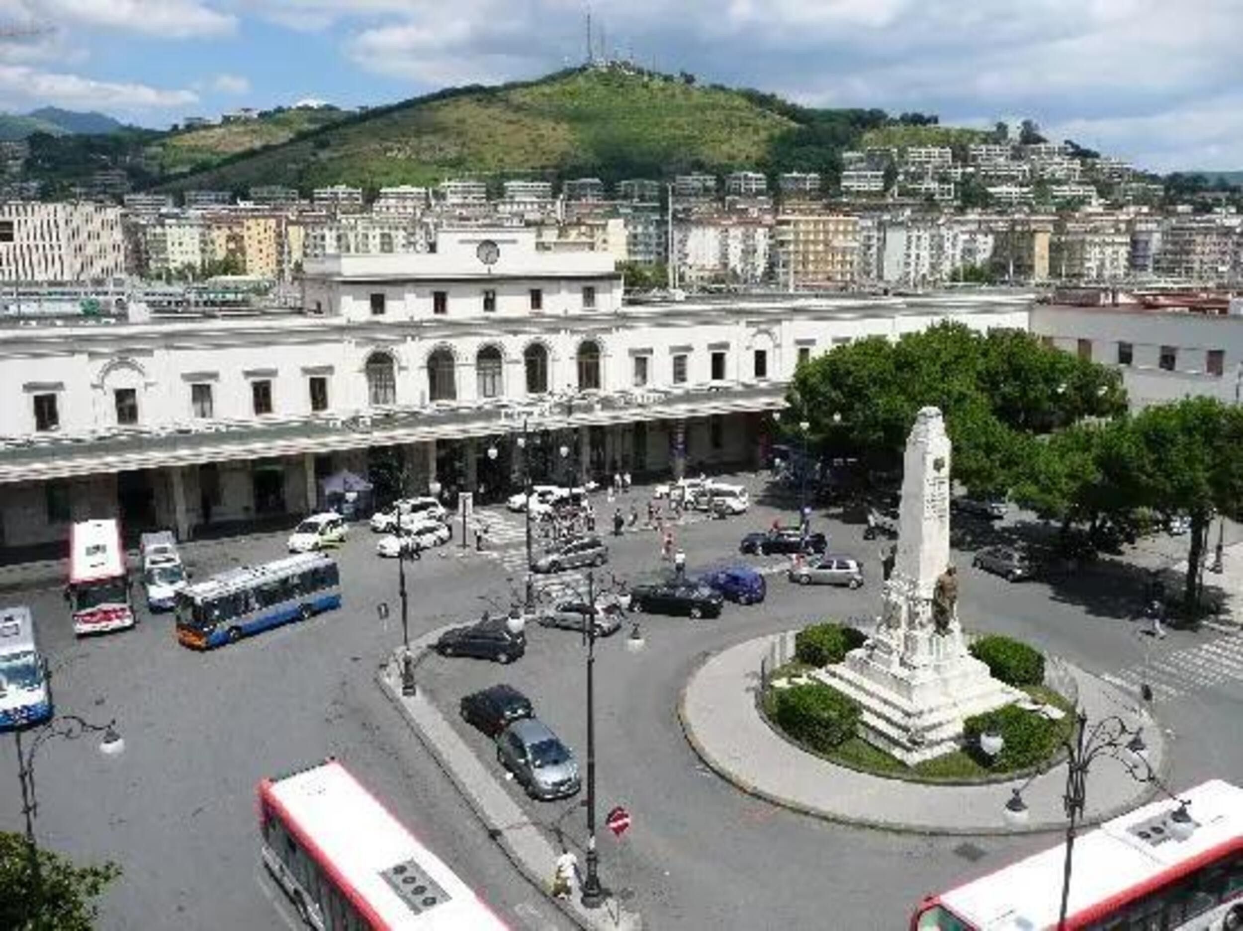 A cityscape with a central roundabout, a prominent white monument, and surrounding buildings.