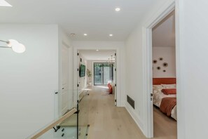 A modern hotel corridor with a glass railing, a bed with red bedding, and a view of the outdoors. - 5BD High Park Retreat w/ Home Theatre, Game Room & Deck (Toronto)