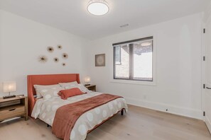 Une chambre à coucher comprenant un lit, des tables de chevet, une fenêtre et des éléments décoratifs sur les murs.