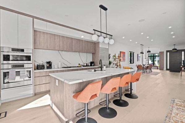 Une cuisine moderne dotée d’un îlot central, de tabourets de bar et d’un coin repas avec une table et des chaises.