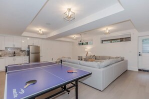 Un espace de vie moderne comprenant une table de ping-pong, un canapé et un coin cuisine.