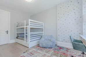 Une chambre avec des lits superposés, un bureau, une chaise et un tapis à motifs.