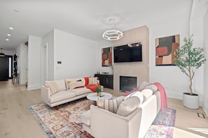 A modern living room with a sofa, coffee table, and a fireplace. - 5BD High Park Retreat w/ Home Theatre, Game Room & Deck (Toronto)
