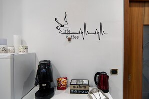 Una pared decorada con motivos de café, que incluye una taza de café y una representación del ritmo cardíaco, además de una máquina de café sobre una encimera.