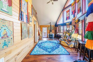 Un pasillo con paredes de madera, un tapete azul estampado y diversas decoraciones religiosas y culturales.