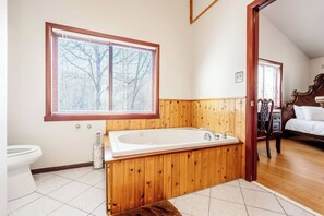 Ein Badezimmer mit einem Holzbadezimmerhocker, einer Badewanne und einer Toilette.