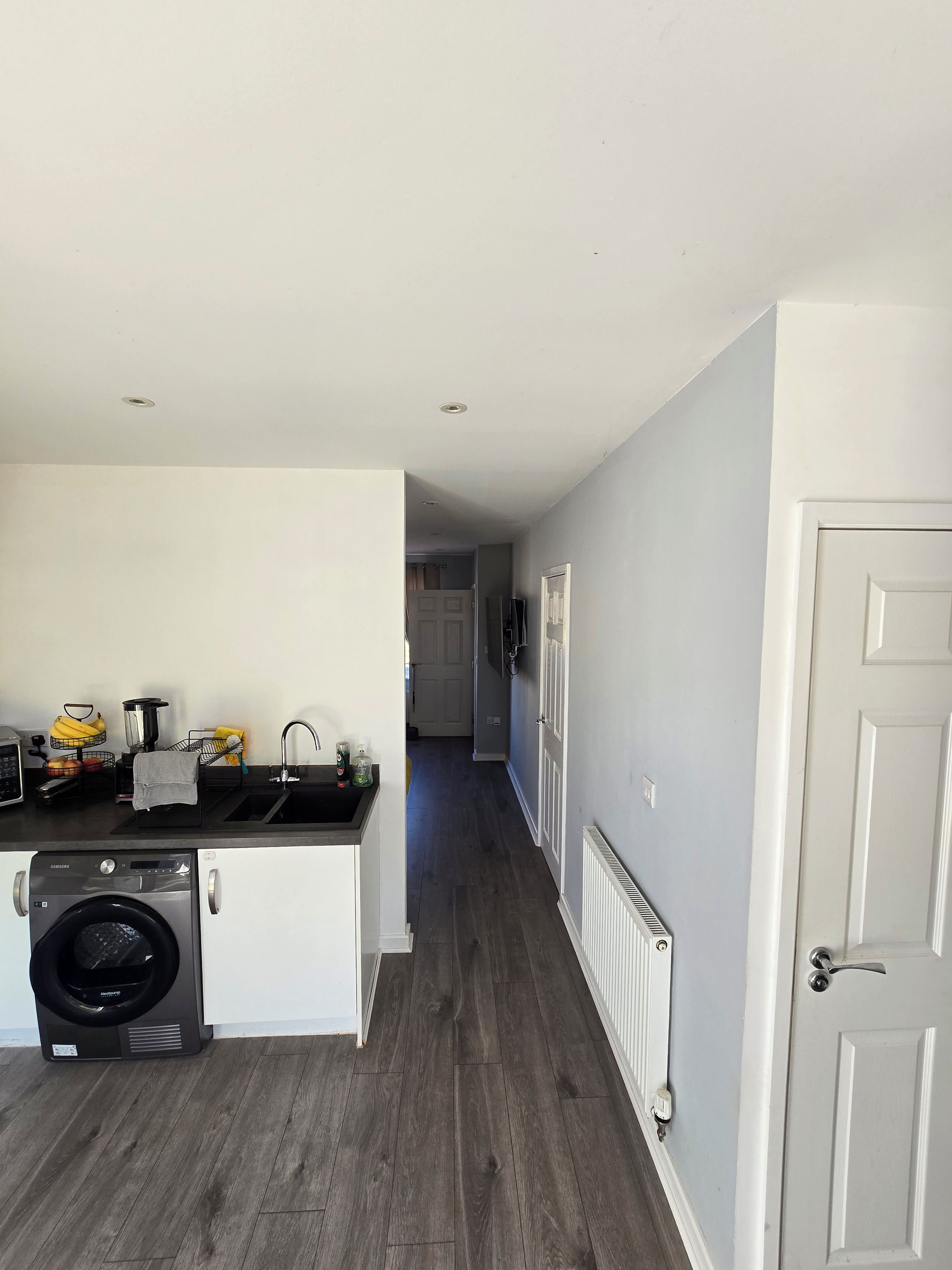 A kitchen with a washing machine, a sink, and a countertop with various items.
