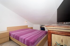 Ein Schlafzimmer mit einem Bett, Holznachttischen, einer Kommode und einem Fernseher.