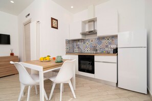 Een moderne keuken met witte kasten, een betegelde spatwand en een ingebouwde oven.