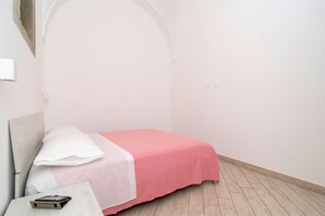 A small, single-bed room with a pink bedspread, white pillows, and a wooden floor. - Nonna Mary - Ulivo by Espresso Rentals (Sant'Agata Sui Due Golfi)
