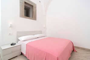 Ein Schlafzimmer mit einem Bett, einem Nachttisch und einem kleinen Fenster.
