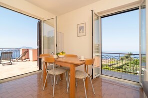 Ein Balkon mit Esstisch, Stühlen und Meerblick.