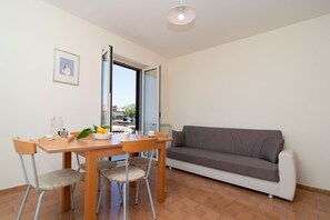 Uma sala de jantar com mesa, cadeiras e um sofá.