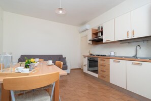 Cozinha moderna com área de jantar, incluindo mesa posta para dois, sofá e mesa de centro.