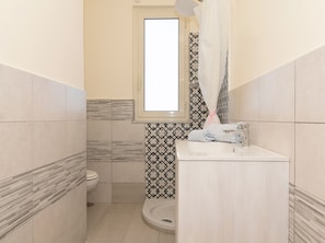 Ein Badezimmer mit Toilette, Waschbecken und Duschbereich.
