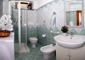 Een badkamer met een douche, toilet, bidet en wastafel.