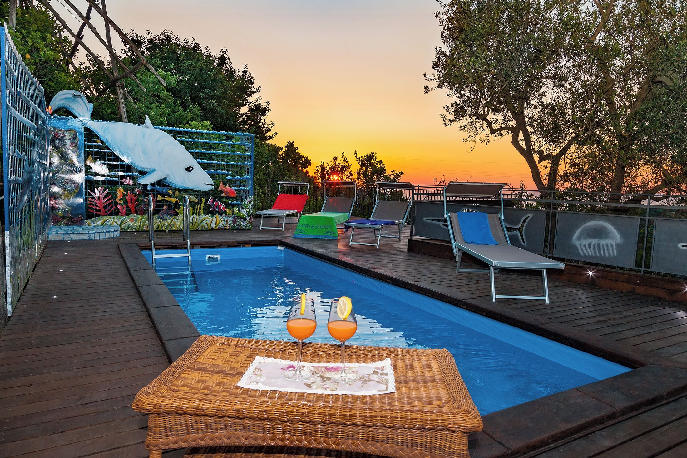 A swimming pool with lounge chairs and a decorative fish sculpture.