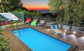 A swimming pool with a wooden deck, lounge chairs, and a decorative shark mural. - Villa Rosanto by Espresso Rentals (Arenaccia)