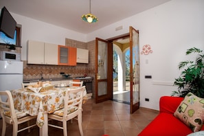 A kitchen with a dining table, chairs, and a red sofa. - Villa Rosanto by Espresso Rentals (Arenaccia)
