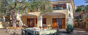 Een villa in mediterrane stijl met buitenmeubilair, een stenen muur en een boom.