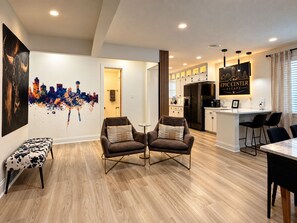 Un salon moderne avec deux fauteuils, un banc et une table à manger.