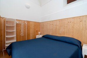 A bedroom with a bed, a wardrobe, and a bedside table. - Vitamin Sea by Espresso Rentals (Napoli)